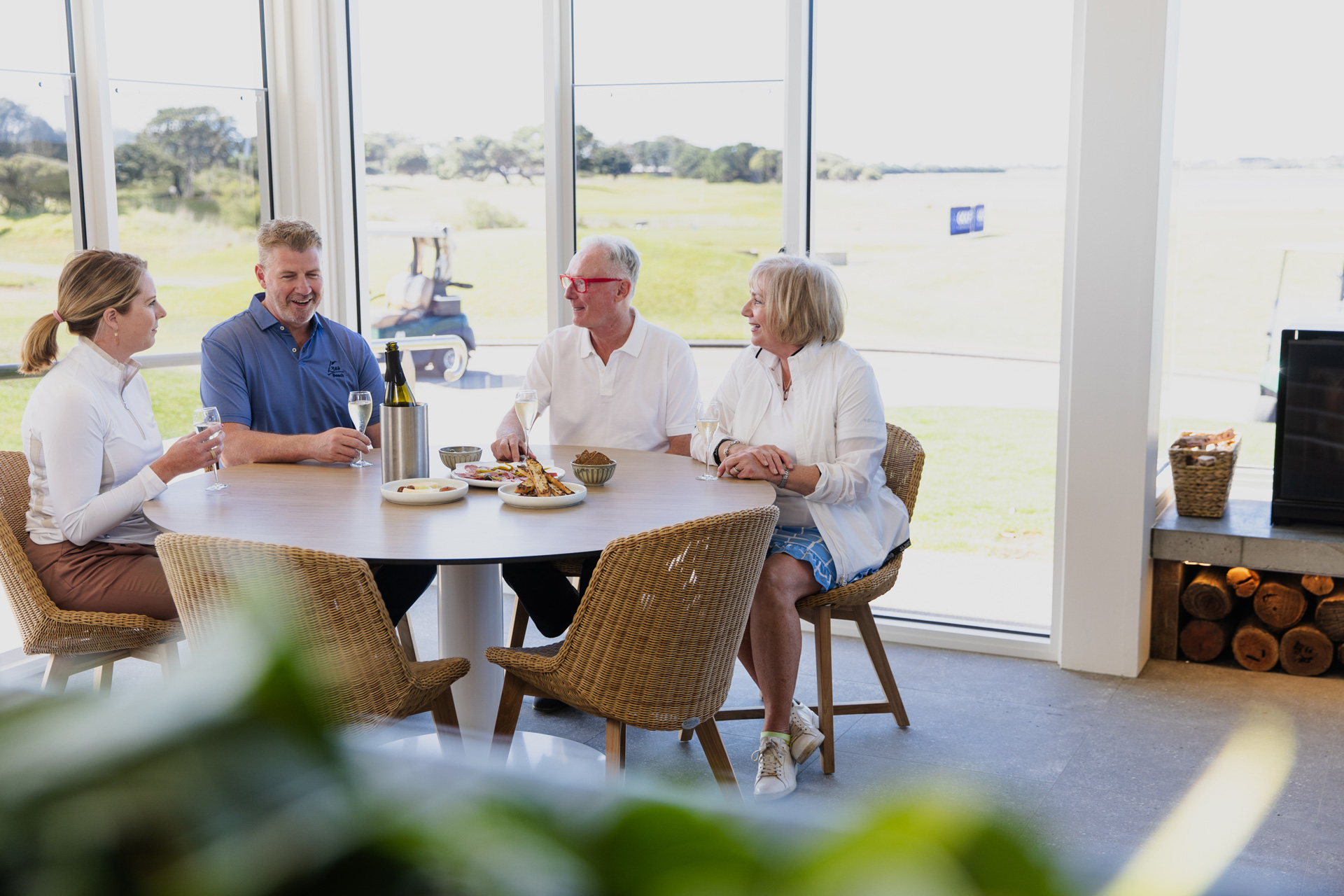 Guests dining beside windows overlooking the golf course at 13th Beach Restaurant